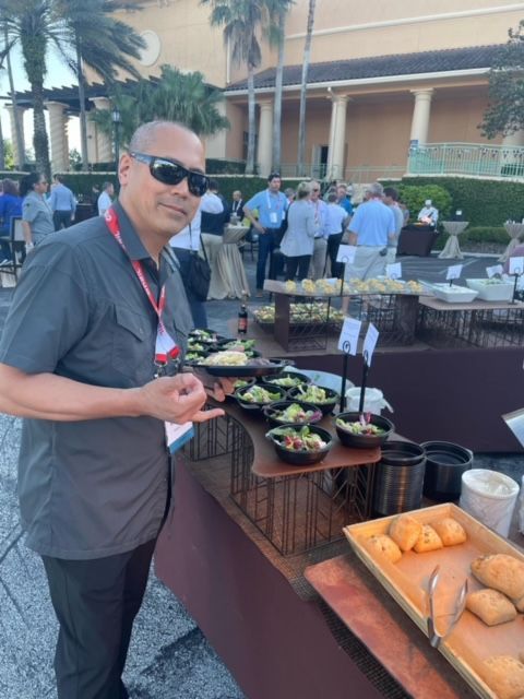A man wearing sunglasses stands in front of a buffet table