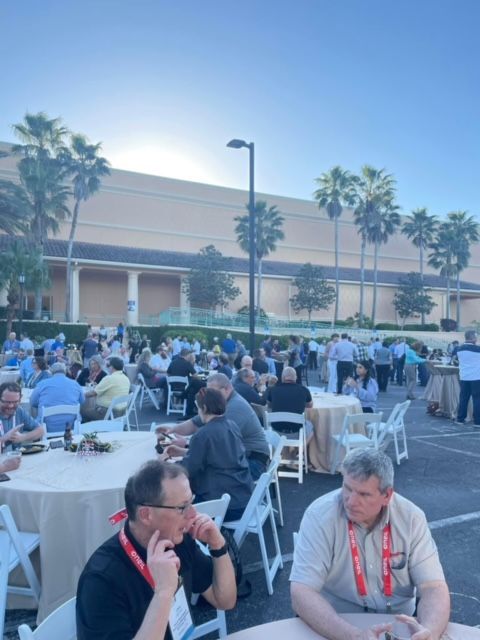 A group of people are sitting at tables in a parking lot