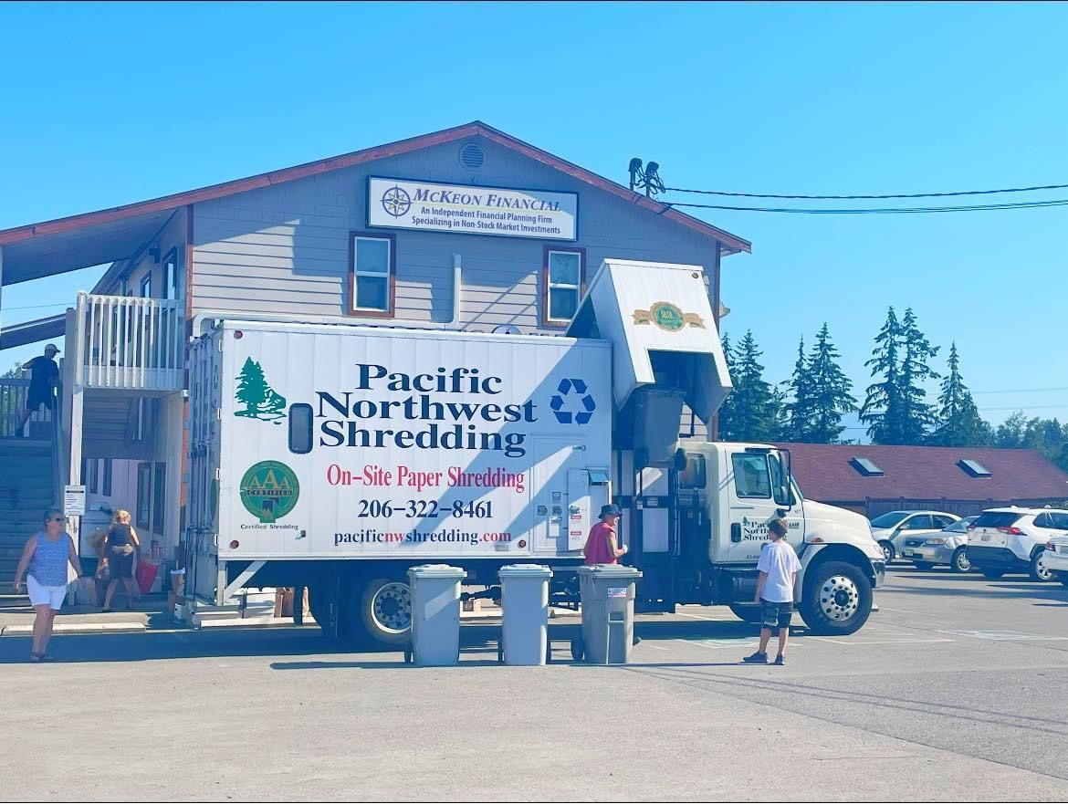 A pacific northwest shredding truck is parked in front of a building