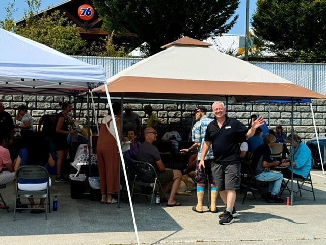 A man is standing in front of a group of people under a tent.