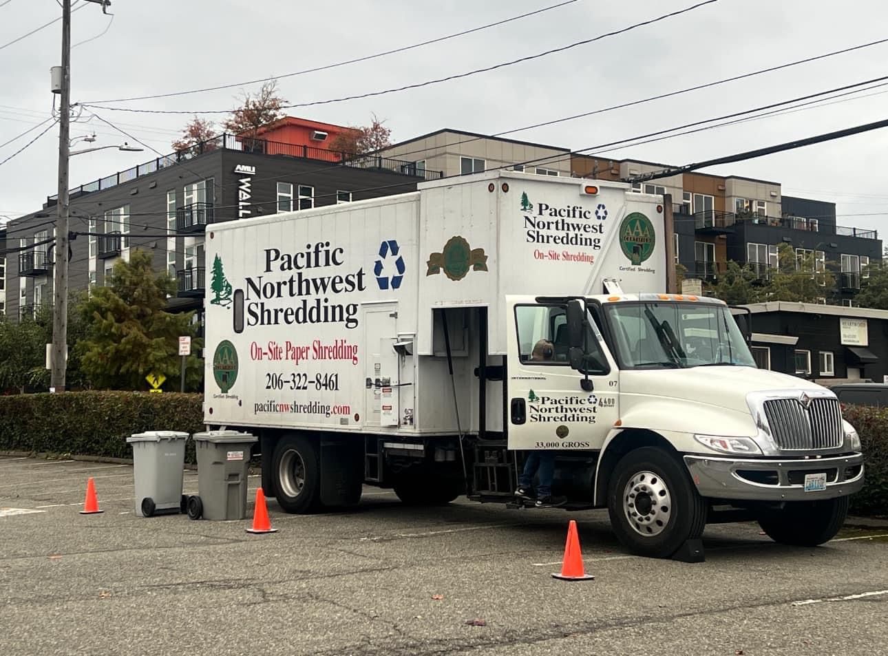 A pacific northwest shredding truck is parked in a parking lot.