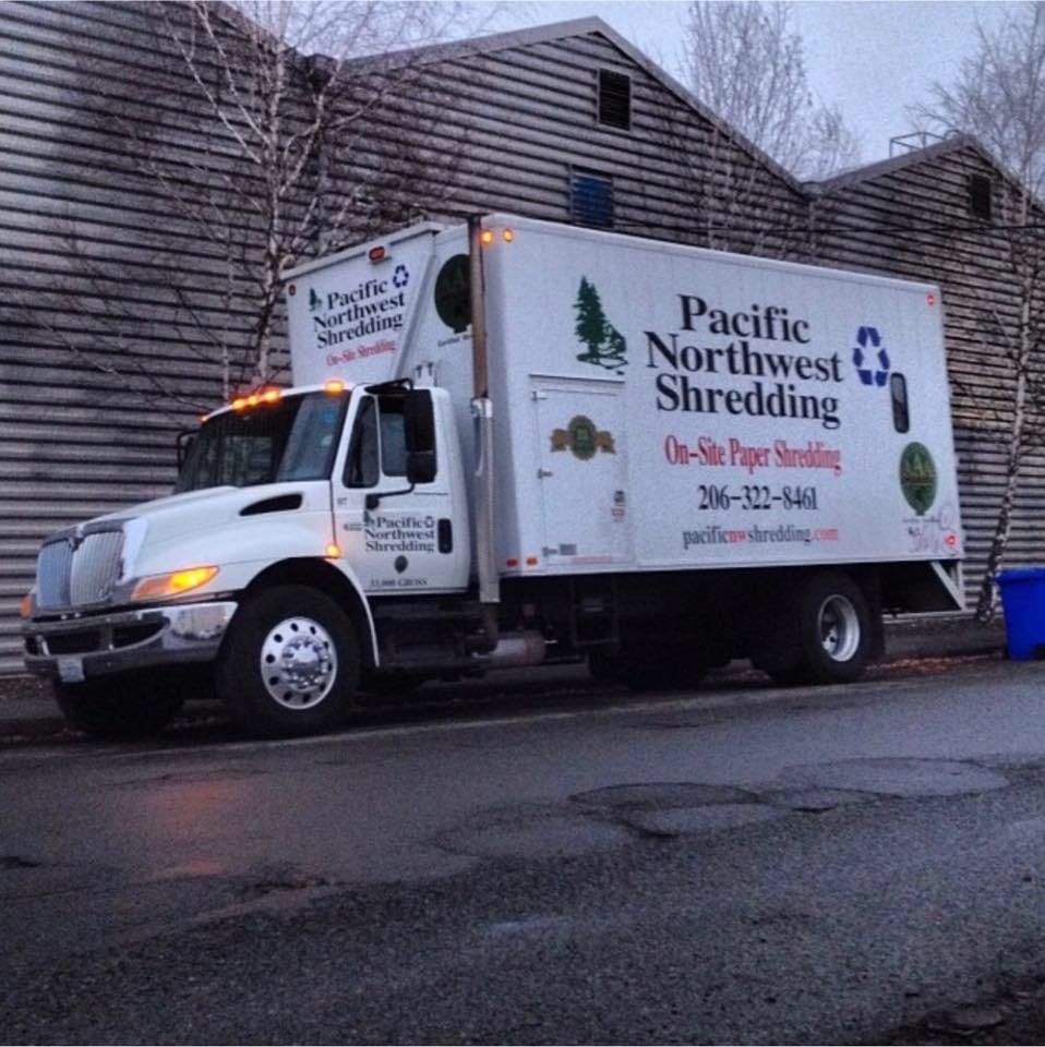 A pacific northwest shredding truck is parked in front of a building
