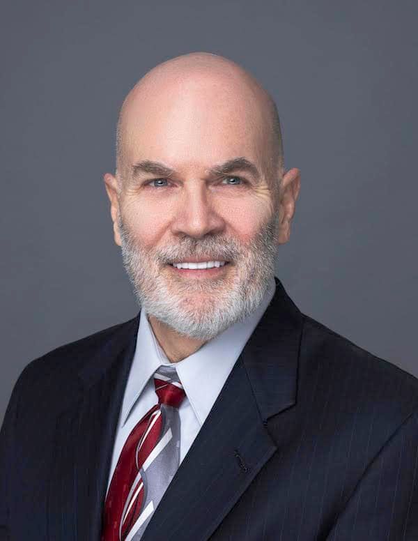 A bald man with a beard is wearing a suit and tie.