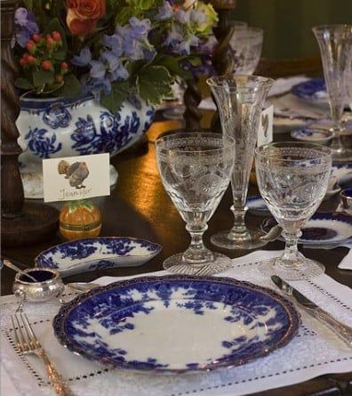 A table set with plates glasses and a vase of flowers