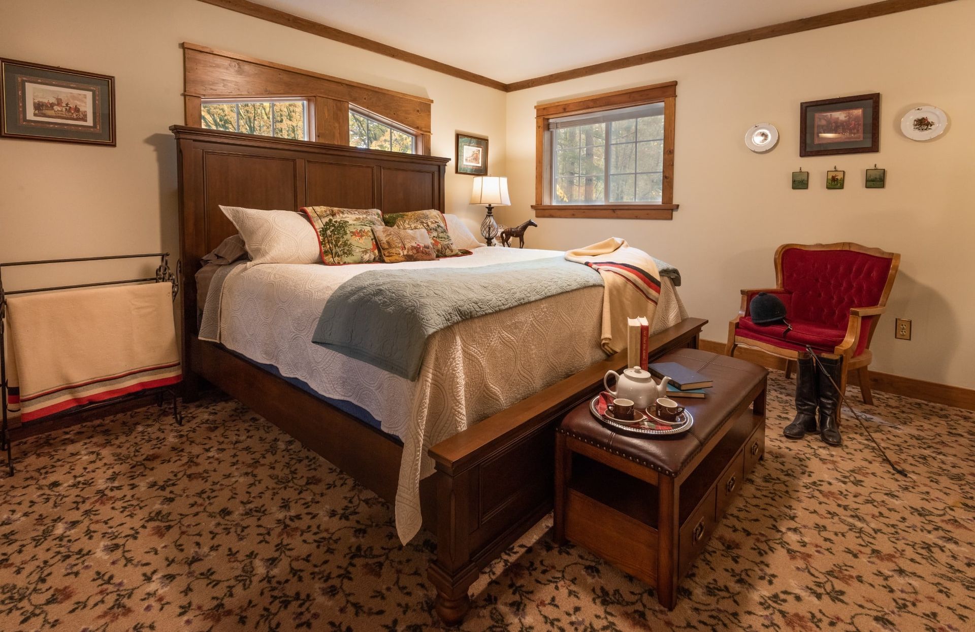A bedroom with a king size bed , chair , coffee table and window.