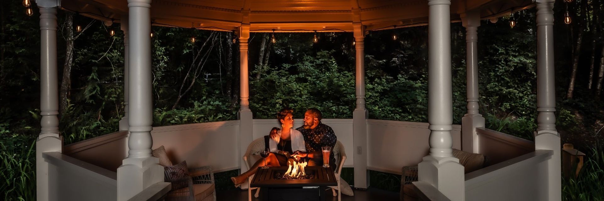 A couple is sitting in a gazebo with a fire pit.