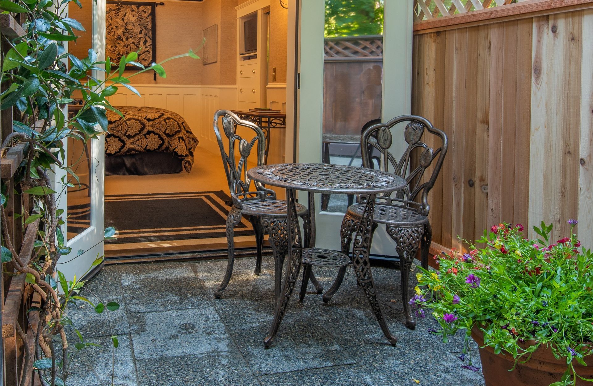 A small patio with a table and chairs in front of a bedroom.