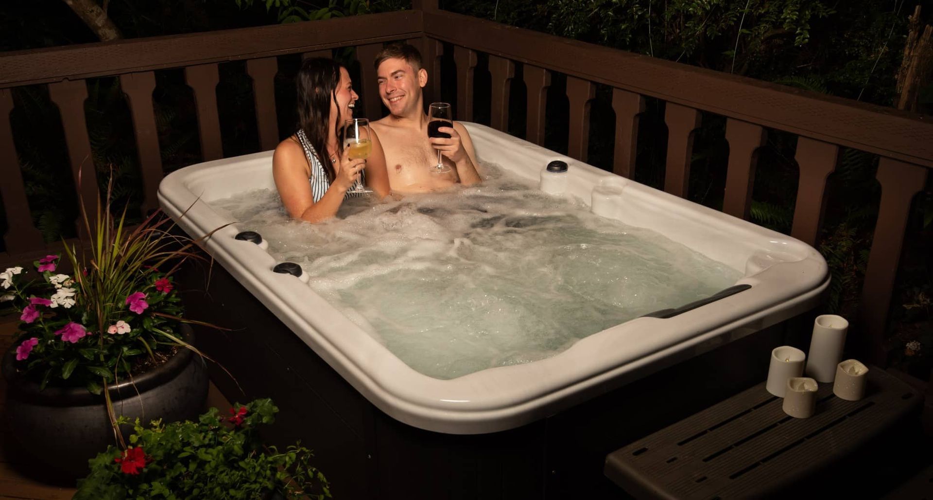 A man and a woman are sitting in a hot tub on a deck.