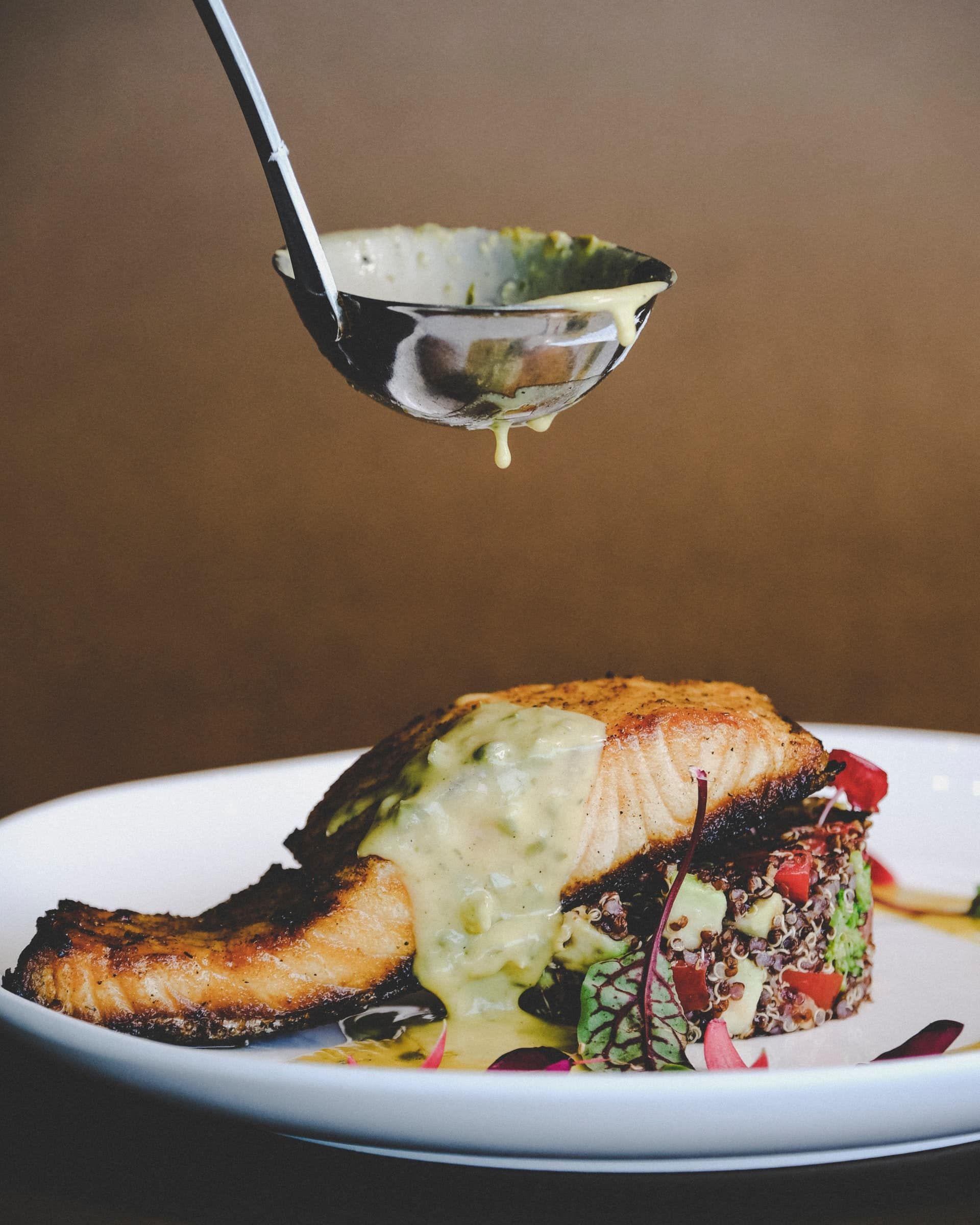 A ladle is being used to pour sauce on a plate of food