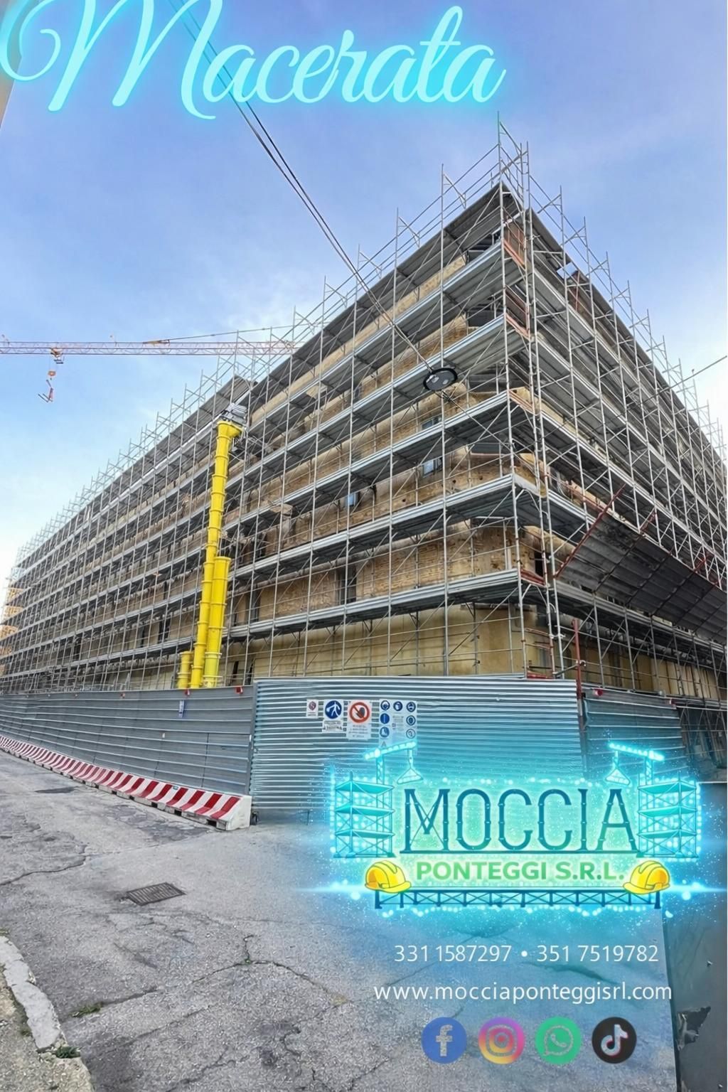 Un edificio a più piani in costruzione a Macerata, completamente ricoperto da impalcature metalliche grigie.