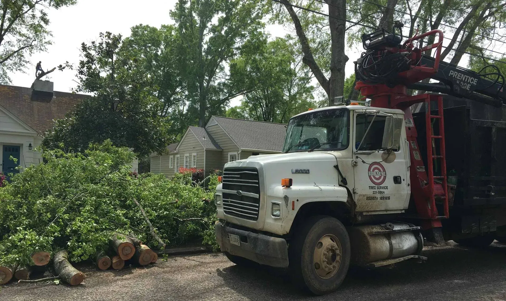 A white truck with a red crane is parked in front of a house.