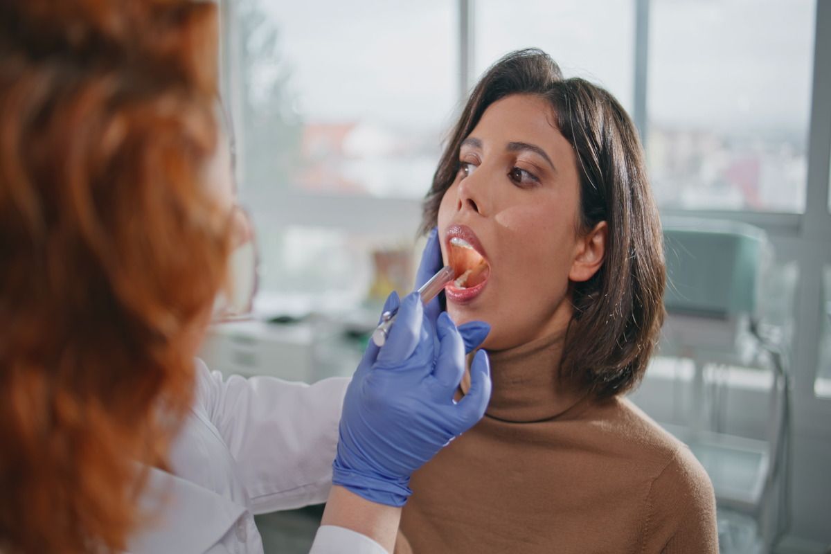 A woman is getting her throat examined by a doctor.