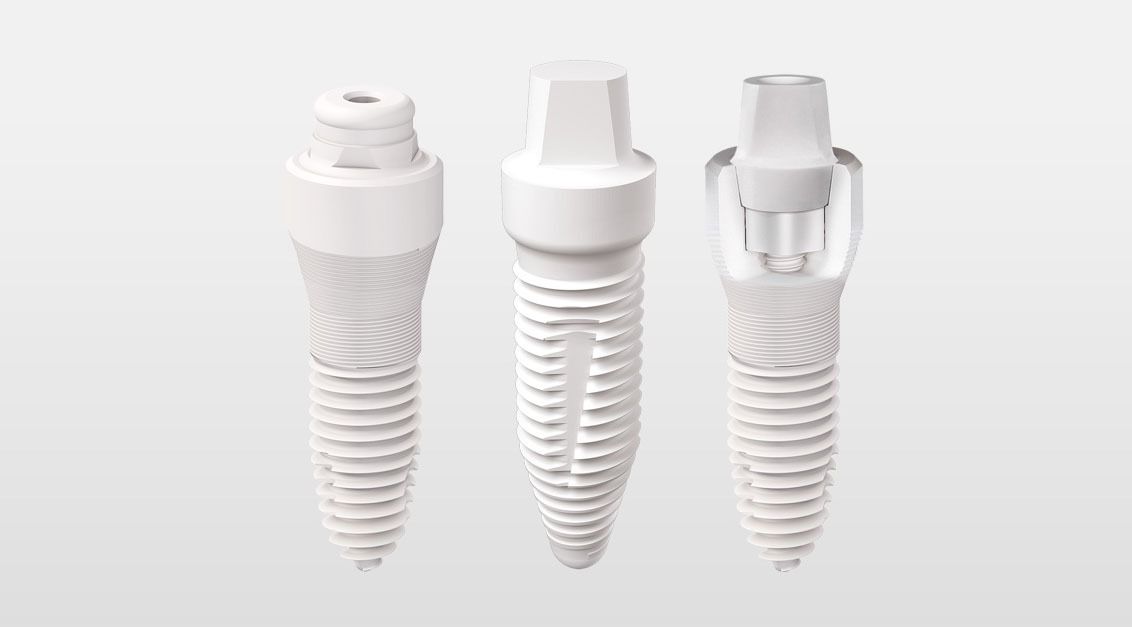 Three white dental implants are sitting next to each other on a white surface.