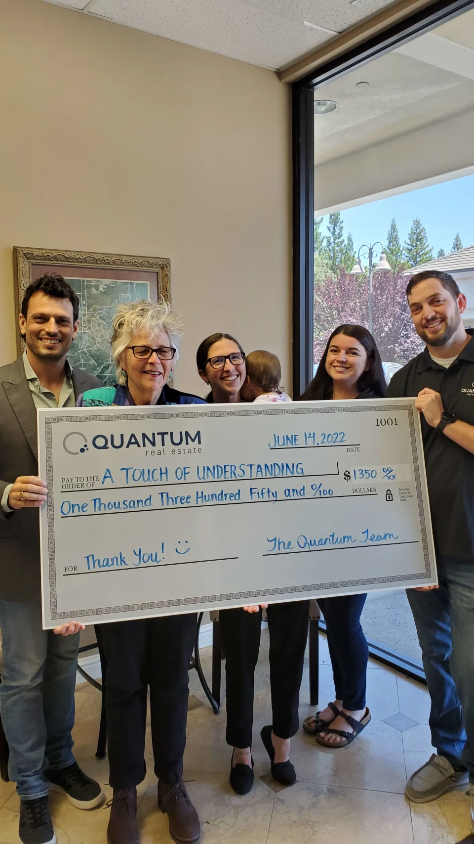 People hold a large check. Quantum donates money to