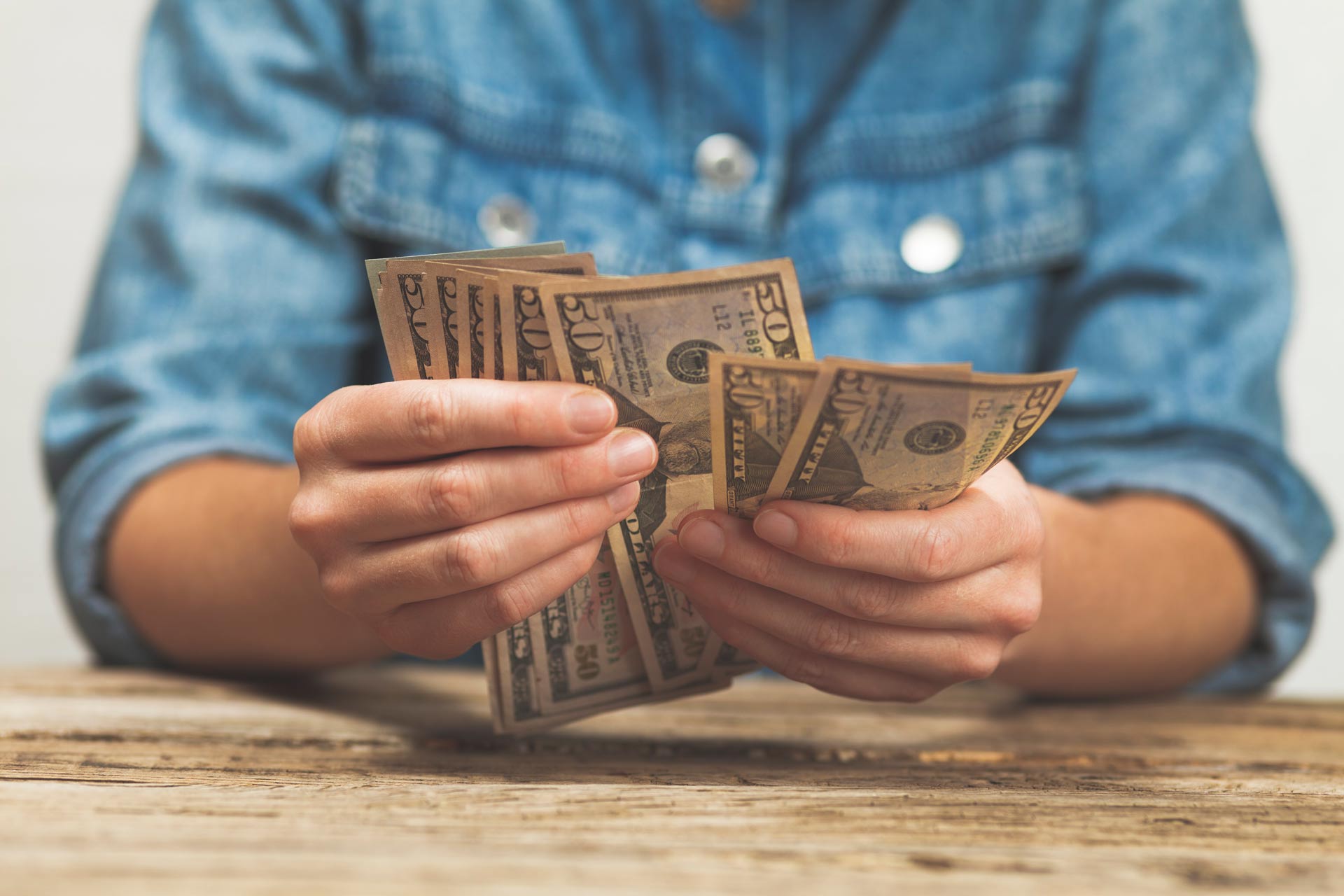 A person is holding a bunch of money in their hands.