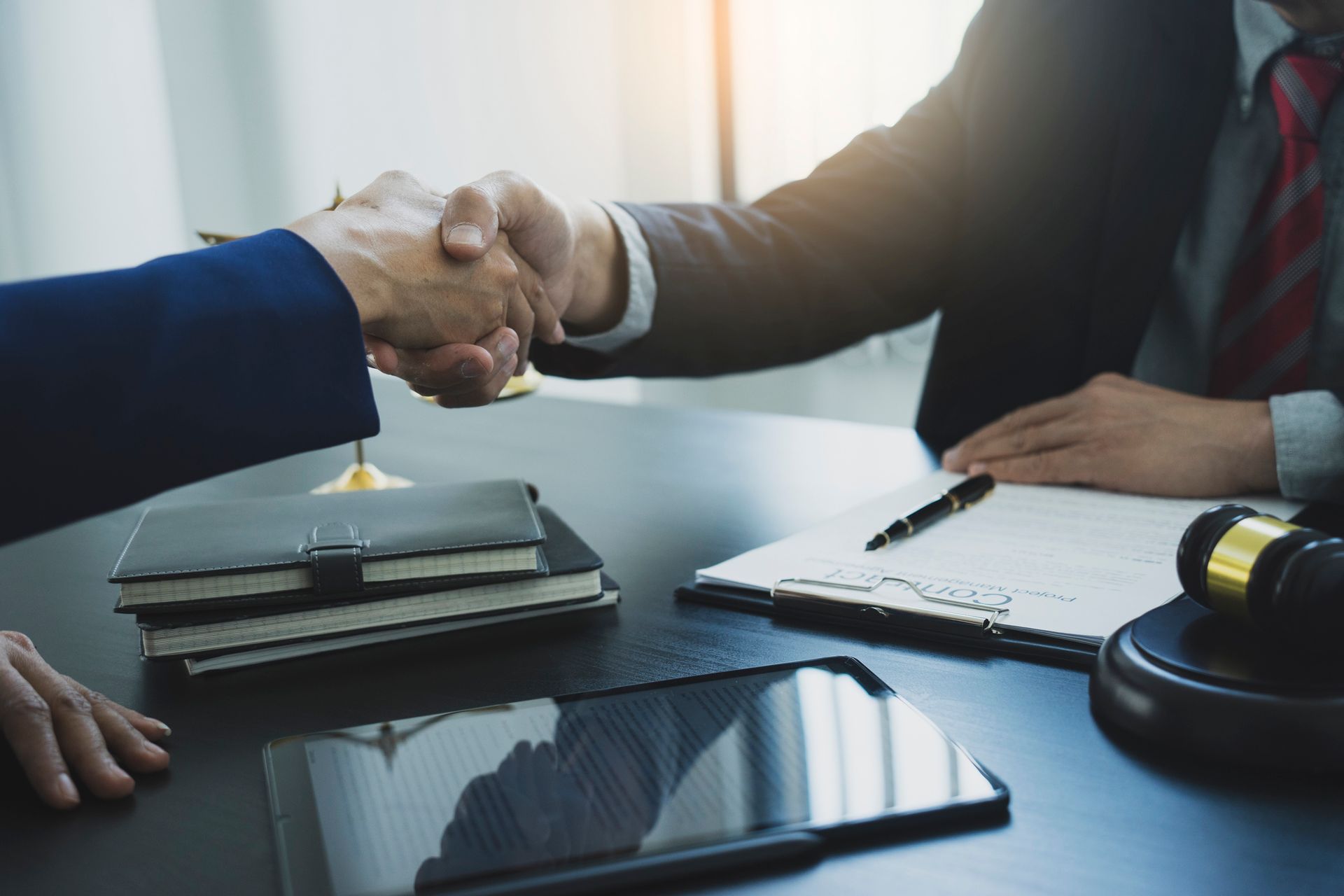 A man and a woman are shaking hands over a table.