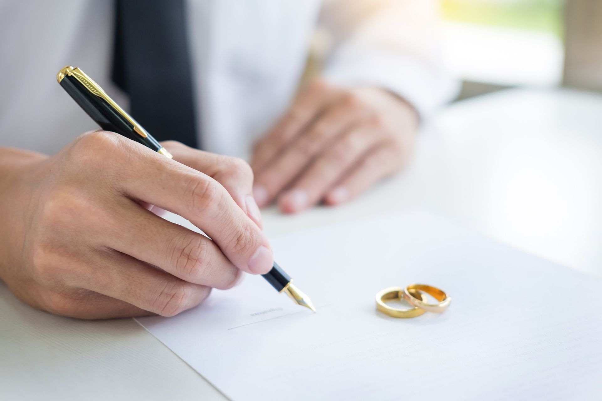 A man is writing on a piece of paper with a pen.