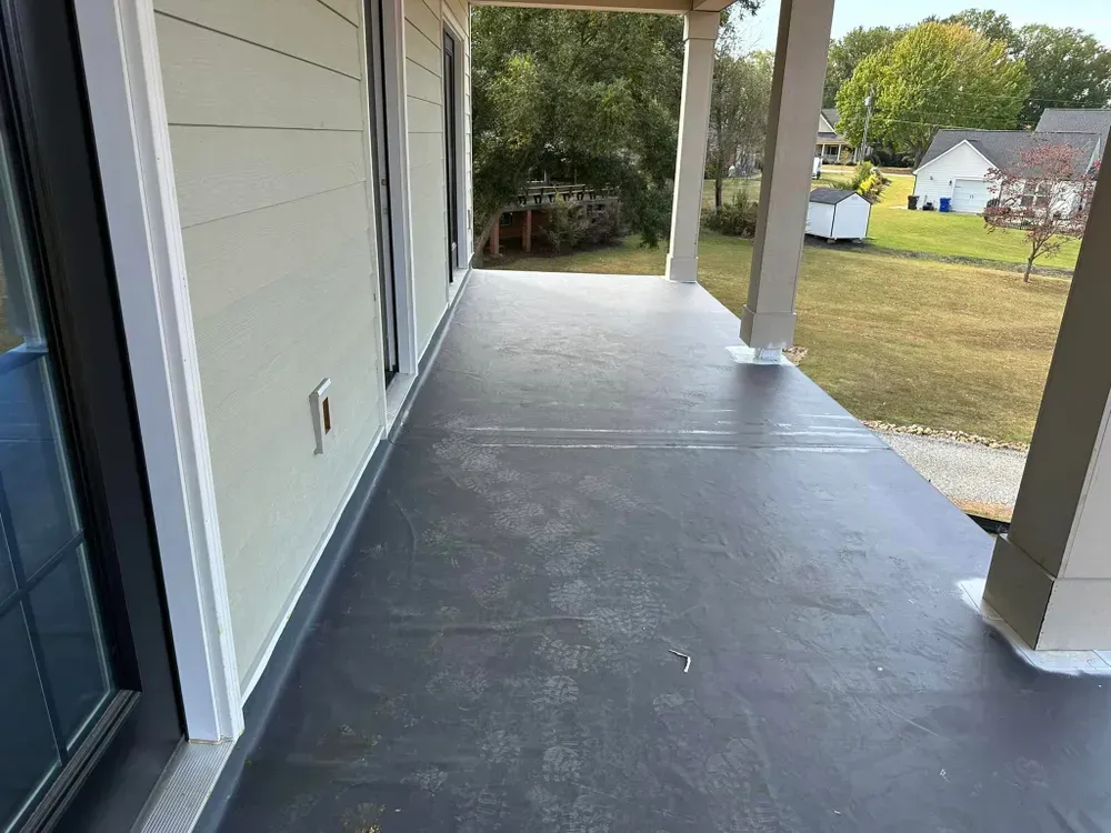 A black porch with a white house in the background.
