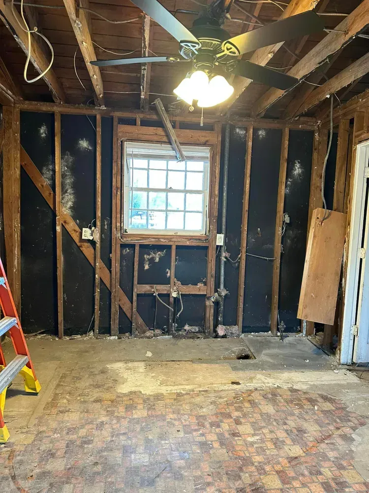 An empty room with a ceiling fan and a window.
