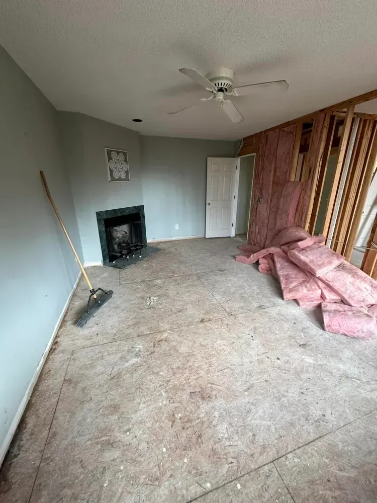 A living room with a ceiling fan and a fireplace under construction.