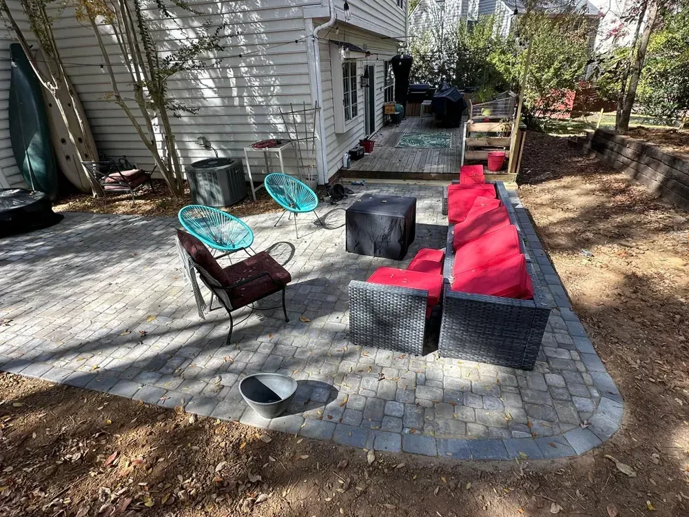 A patio with a couch , chairs , tables and a fire pit.