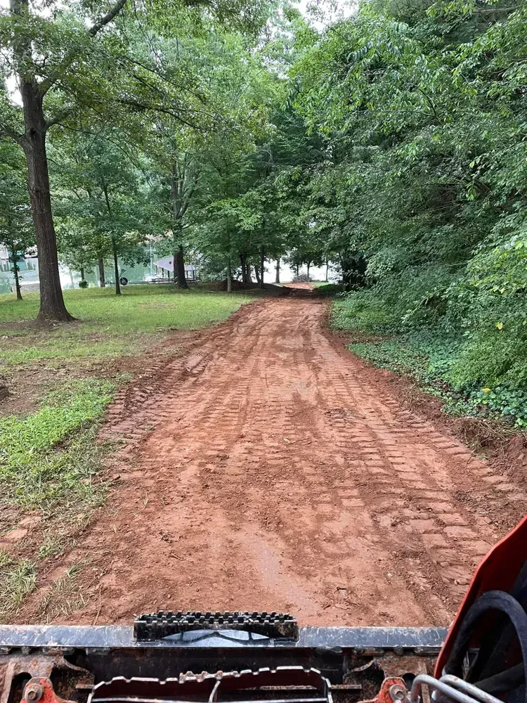 A person is driving a bulldozer down a dirt road.