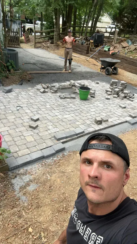 A man is standing in front of a brick patio being built.