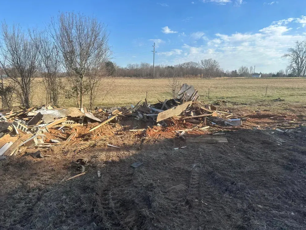 A pile of rubble in a field with trees in the background.