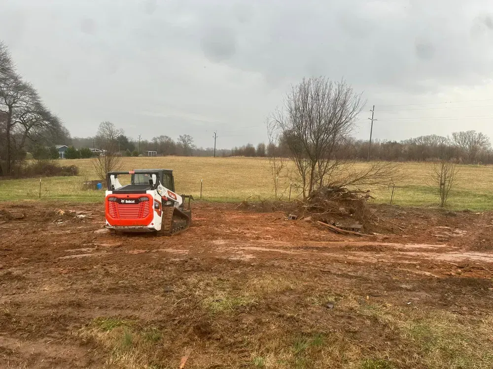 A bulldozer is sitting in the middle of a dirt field.