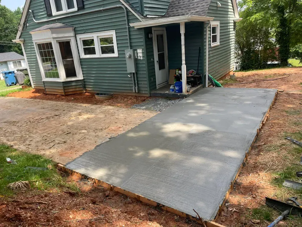 A concrete driveway is being built in front of a house.