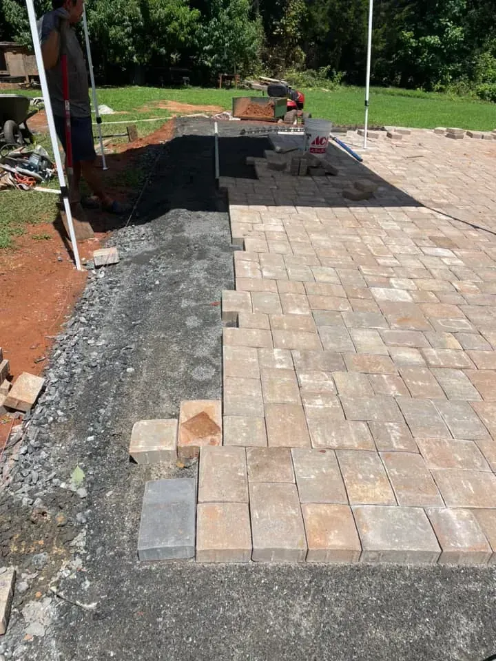 A brick walkway is being built in a backyard.