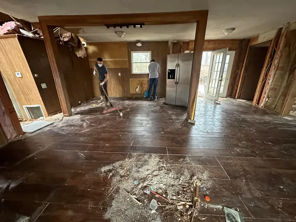A man is sweeping the floor of a room in a house.