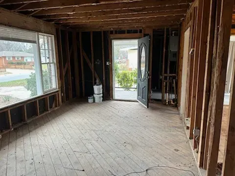 An empty room with a wooden floor and a door in a house under construction.