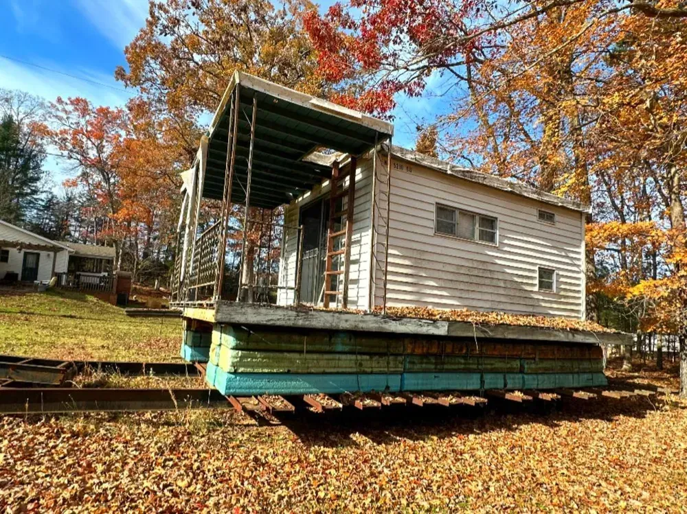 A small house is sitting on top of a train car.