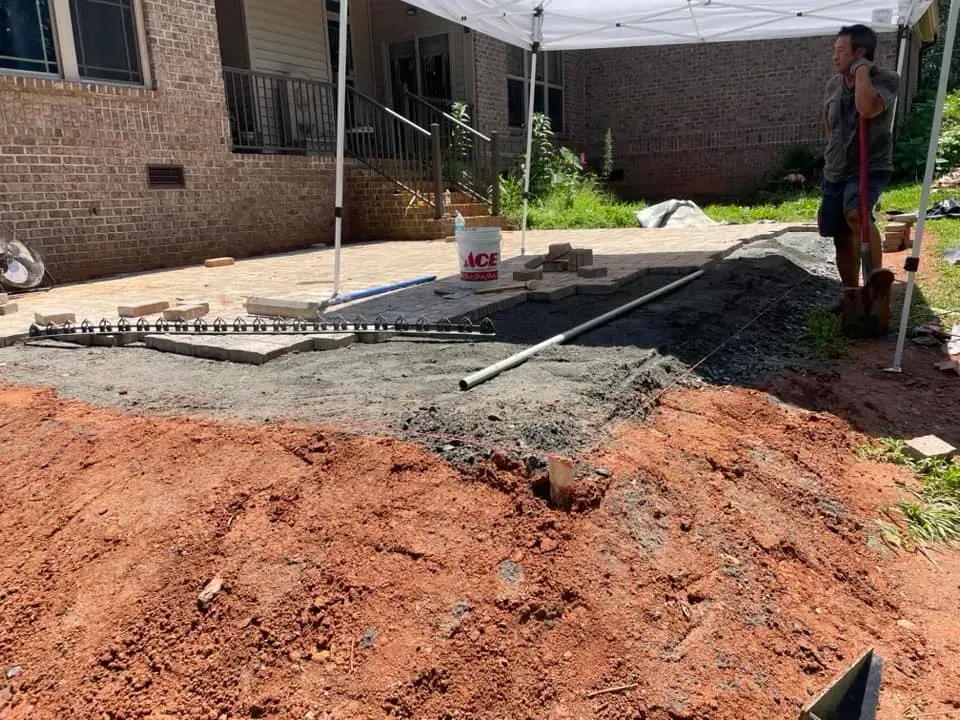 A man is standing in a pile of dirt in front of a house.