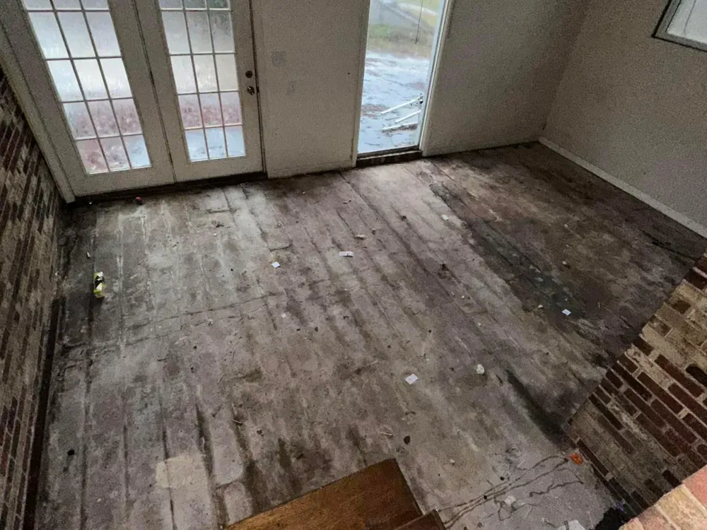 A room with a wooden floor and a brick wall.