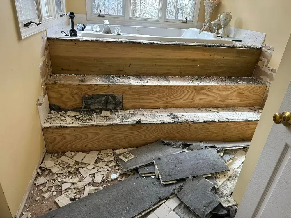 A bathroom with a bathtub and stairs being removed.