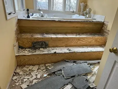 A bathroom with a bathtub and stairs being removed.