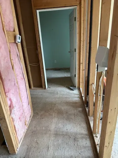 A hallway in a house under construction with a door open.