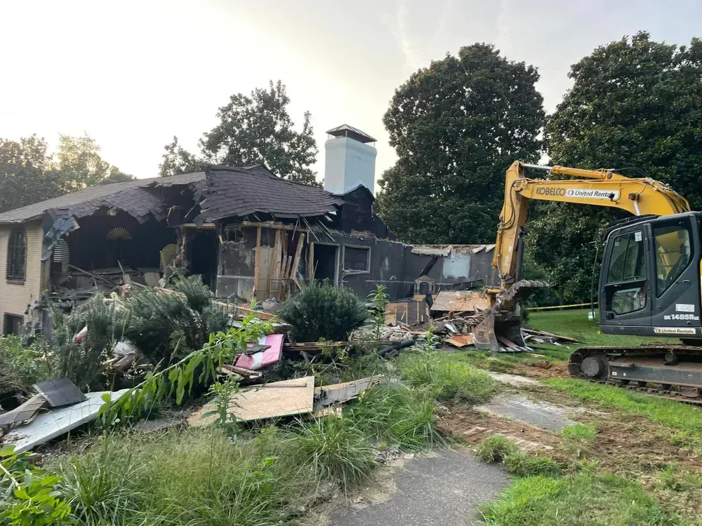 A house is being demolished by an excavator.