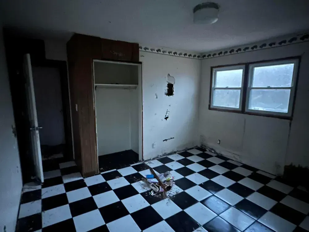 An empty room with a checkered floor and a closet