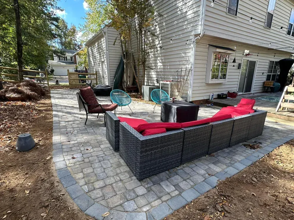A patio with a couch and chairs in front of a house.