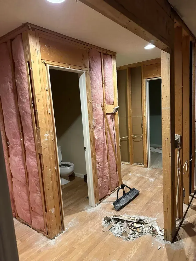A room with pink insulation on the walls and a toilet.