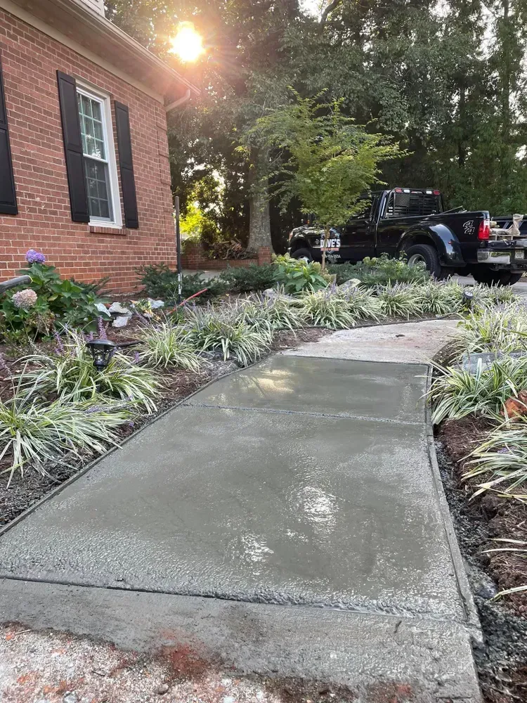 A concrete walkway is being built in front of a brick house.