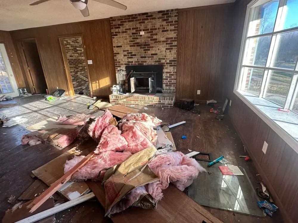 A living room with a fireplace and a lot of junk in it.