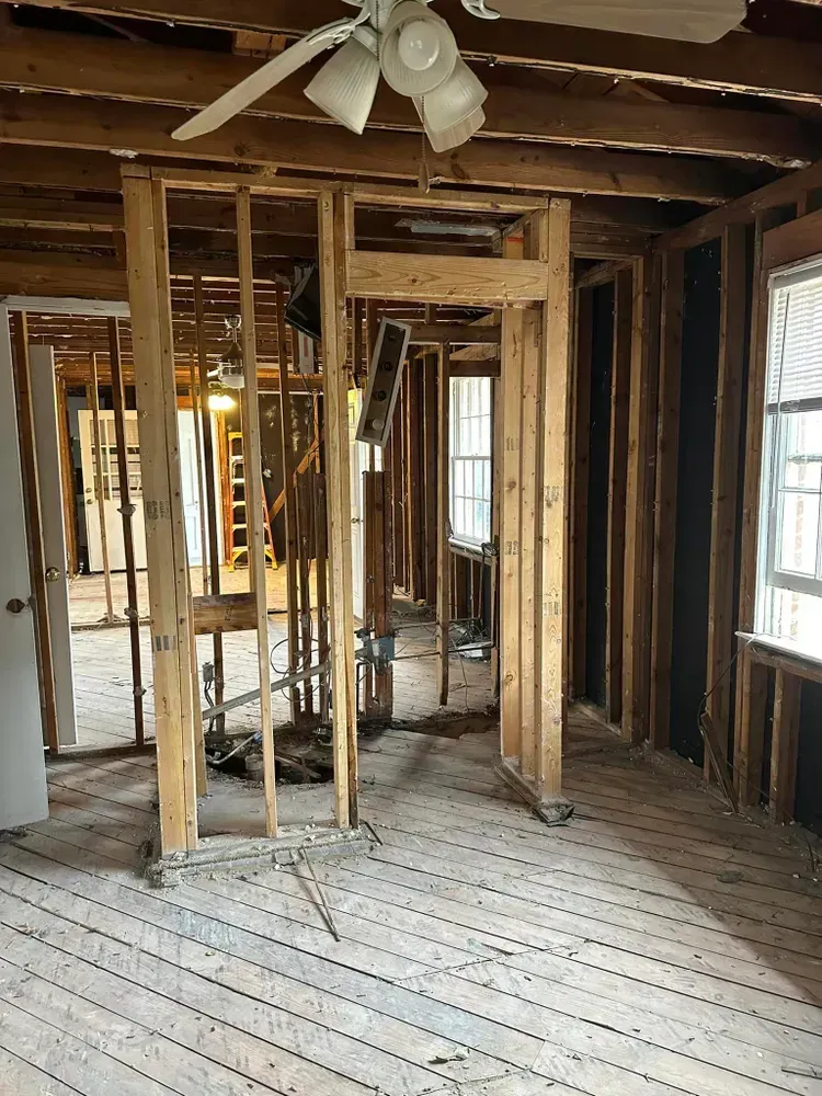 A room in a house under construction with a ceiling fan.
