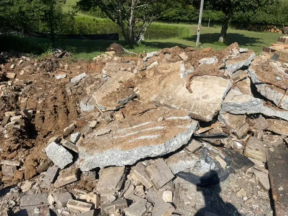 A pile of rocks and dirt in a field with trees in the background.