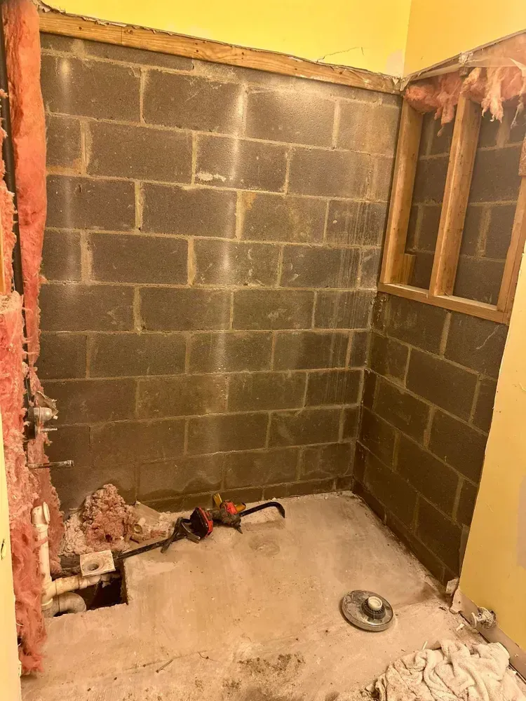 A bathroom under construction with brick walls and a window.