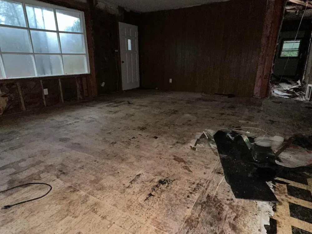 An empty room with a lot of dirt on the floor and a window.