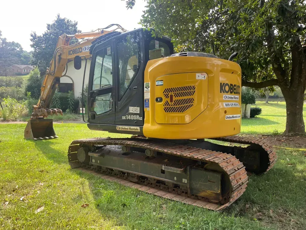 A yellow excavator is parked in a grassy field.